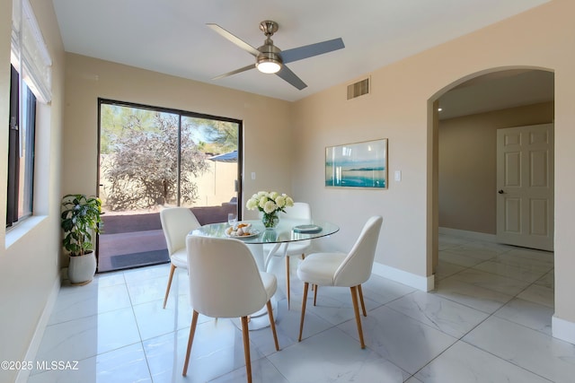 dining room featuring visible vents, baseboards, ceiling fan, arched walkways, and marble finish floor