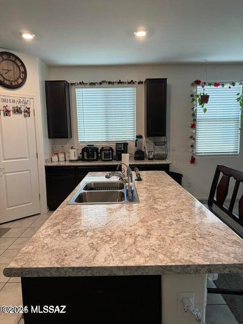 kitchen with a kitchen bar, sink, a kitchen island with sink, and light tile patterned floors