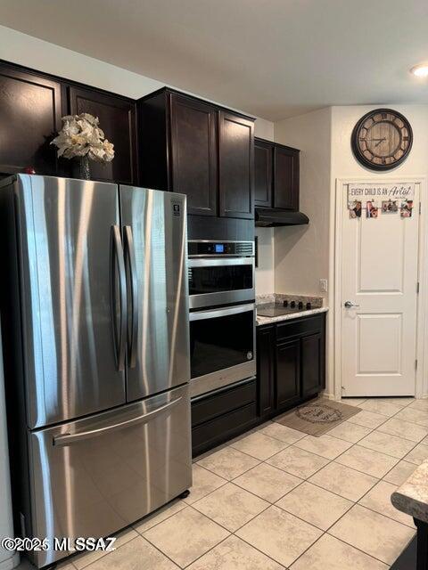 kitchen with light tile patterned floors, dark brown cabinets, and appliances with stainless steel finishes