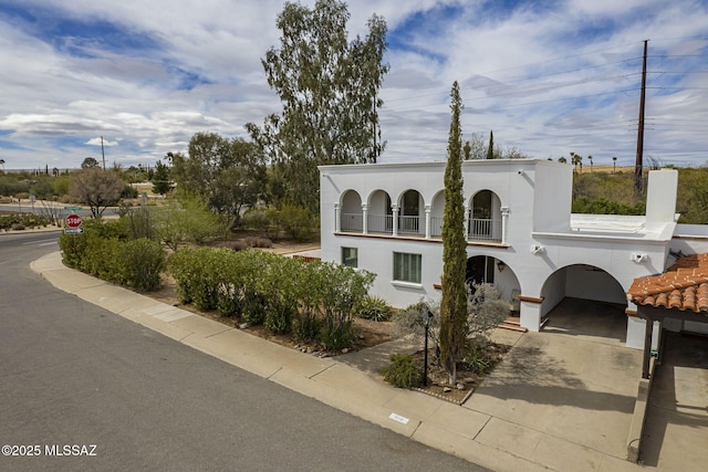 mediterranean / spanish home featuring driveway, a balcony, and stucco siding