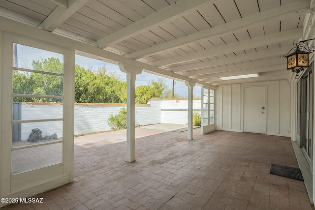 unfurnished sunroom featuring beamed ceiling