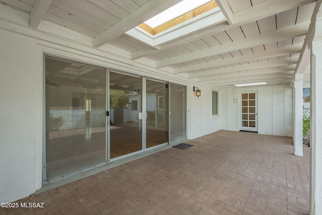 unfurnished sunroom featuring beamed ceiling, a skylight, and wooden ceiling