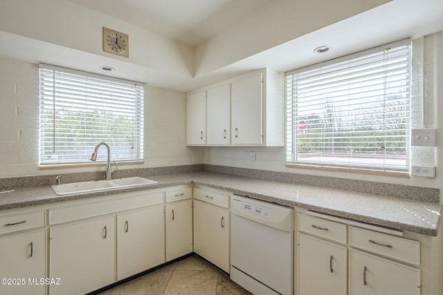 kitchen with light tile patterned floors, white cabinets, white dishwasher, light countertops, and a sink