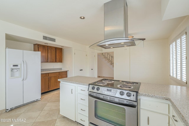 kitchen featuring electric range, visible vents, white fridge with ice dispenser, brown cabinetry, and island exhaust hood