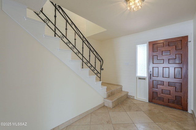 entryway with light tile patterned flooring, baseboards, and stairs