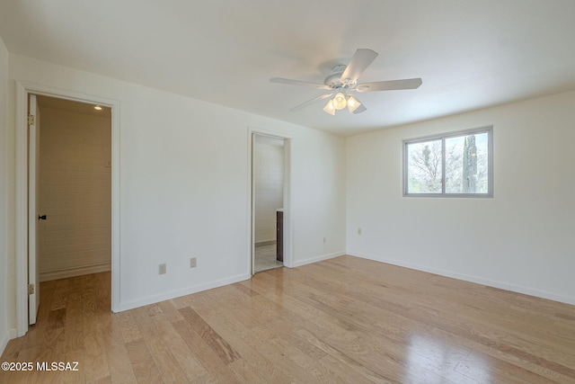 unfurnished bedroom with a walk in closet, a ceiling fan, connected bathroom, light wood-type flooring, and baseboards