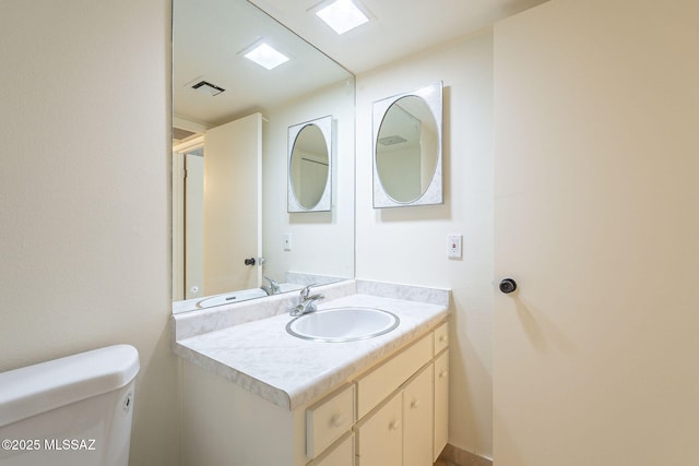 bathroom with toilet, visible vents, and vanity