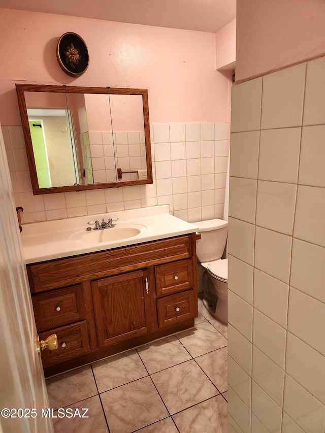 bathroom with tile patterned flooring, vanity, tile walls, and toilet