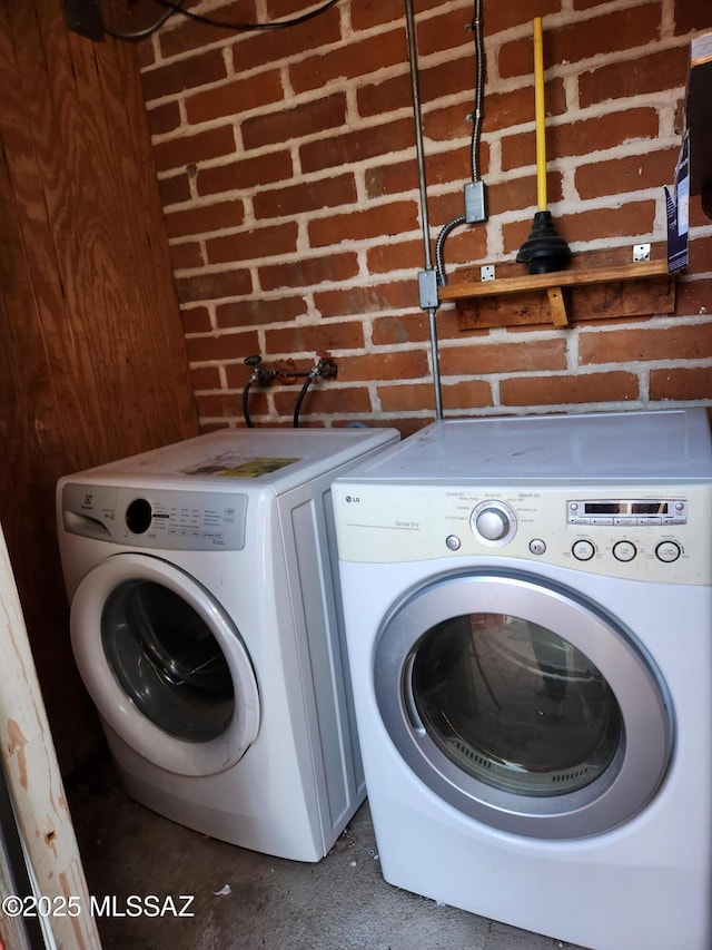 washroom with independent washer and dryer and brick wall