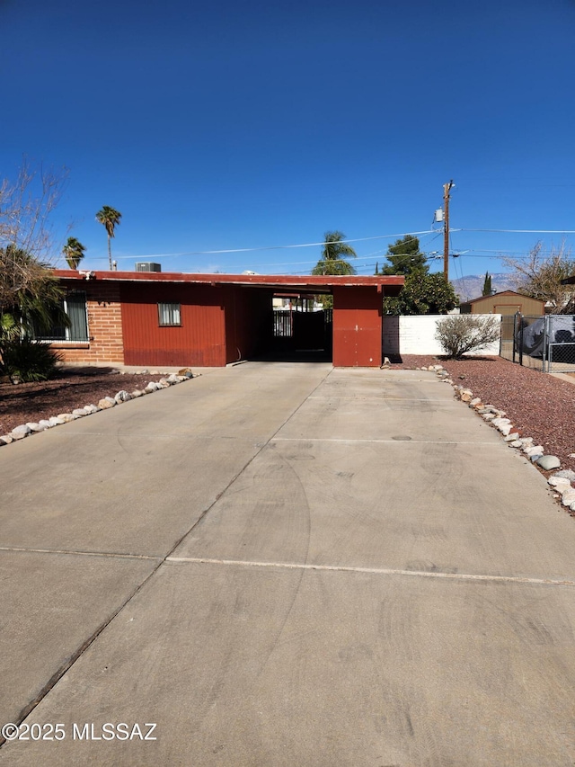 ranch-style home featuring a gate, a carport, driveway, and fence