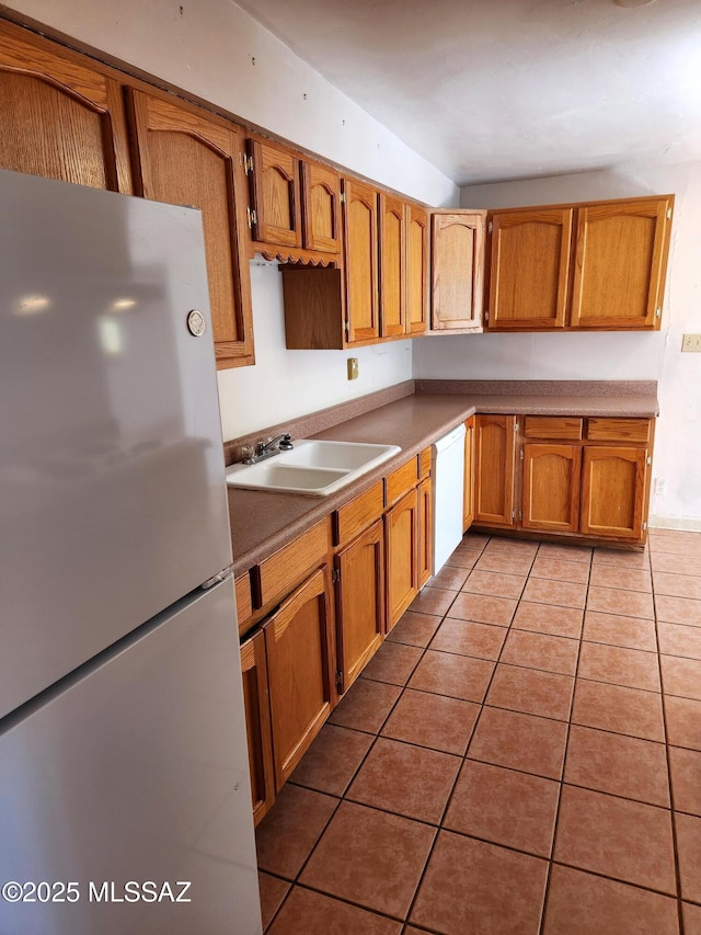 kitchen with white appliances, sink, and light tile patterned floors