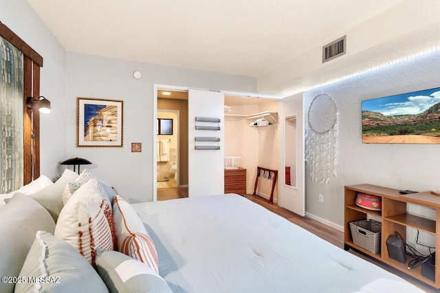 bedroom with wood finished floors, visible vents, and baseboards