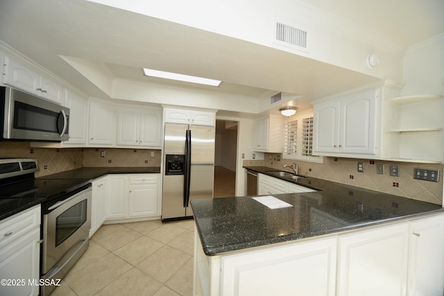 kitchen with white cabinetry, a tray ceiling, stainless steel appliances, and kitchen peninsula