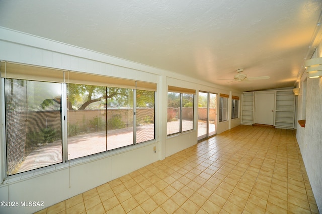 unfurnished sunroom featuring ceiling fan