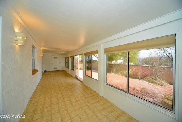 unfurnished sunroom featuring ceiling fan