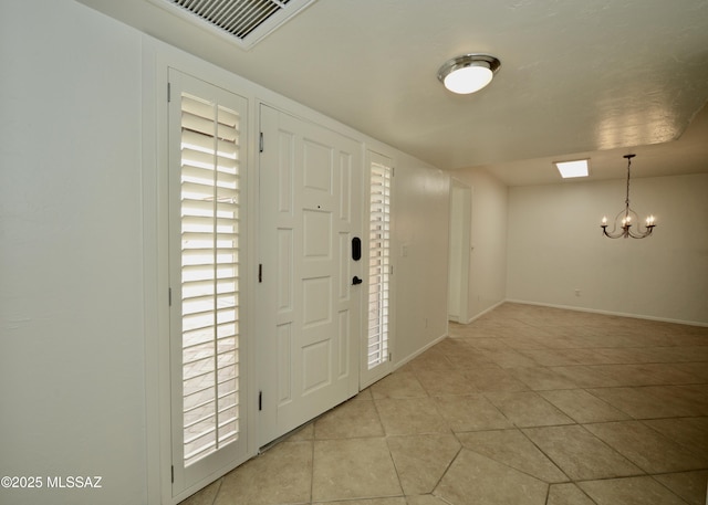 tiled entrance foyer with a notable chandelier