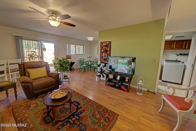 living room with ceiling fan, washer / dryer, and light hardwood / wood-style floors