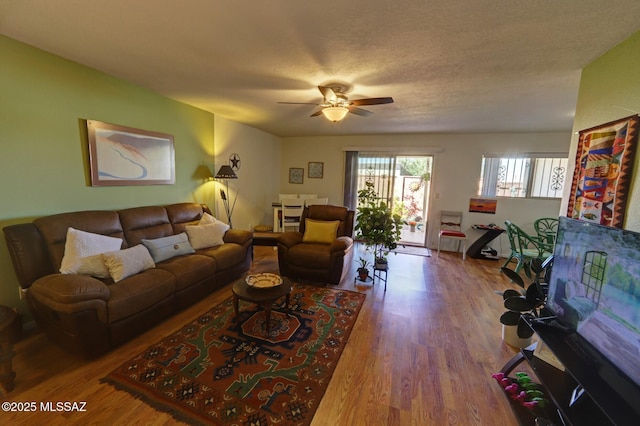 living room with ceiling fan, hardwood / wood-style flooring, and a textured ceiling