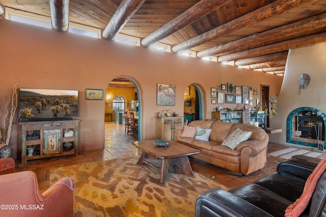 living area featuring arched walkways, wood ceiling, beamed ceiling, and stone tile flooring