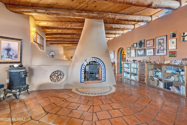 unfurnished living room with wood ceiling, beamed ceiling, arched walkways, and a wood stove