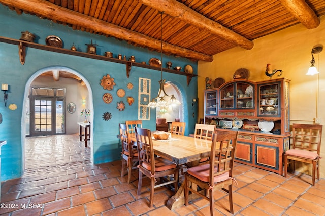 dining space with arched walkways, wood ceiling, and beam ceiling