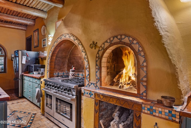 kitchen with stainless steel appliances, wooden ceiling, brick floor, and beamed ceiling