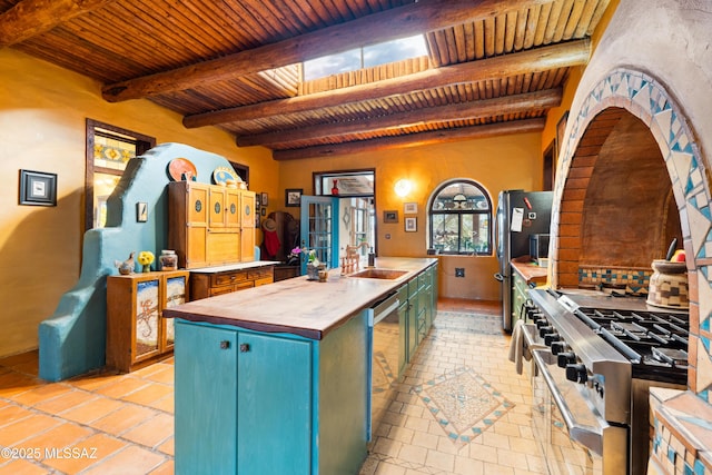 kitchen with wooden ceiling, a sink, wood counters, appliances with stainless steel finishes, and an island with sink