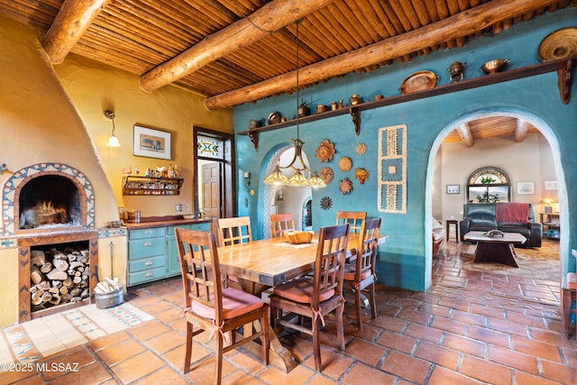 dining area featuring arched walkways, wood ceiling, and beamed ceiling