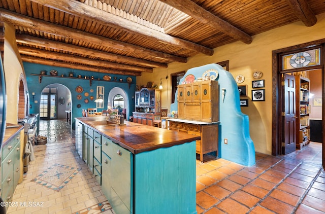 kitchen featuring arched walkways, beamed ceiling, wood counters, and wood ceiling