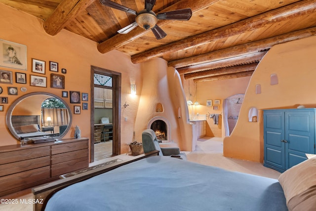 carpeted bedroom with wooden ceiling, a fireplace, and beam ceiling