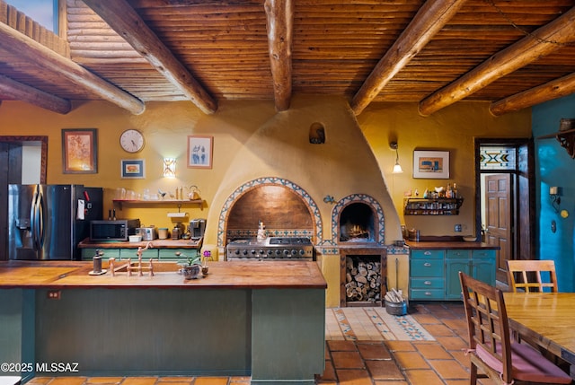 kitchen with stainless steel microwave, wood ceiling, wood counters, refrigerator with ice dispenser, and range