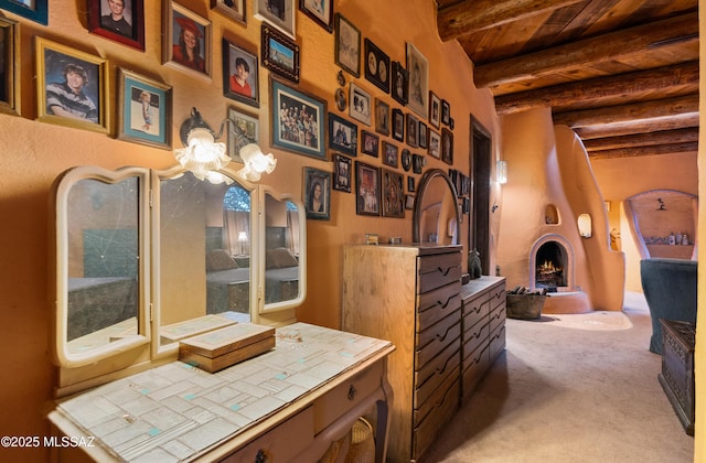 interior space featuring wooden ceiling, a warm lit fireplace, and beam ceiling