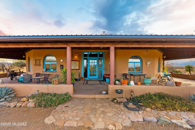 view of exterior entry with a porch and stucco siding