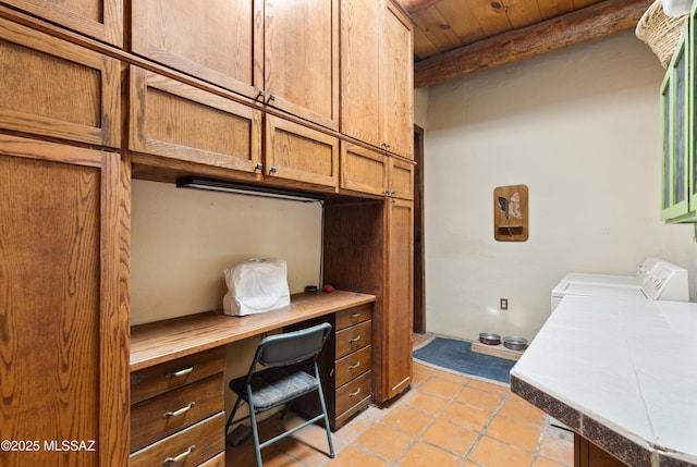 office area featuring light tile patterned floors, washing machine and dryer, built in study area, wooden ceiling, and beamed ceiling