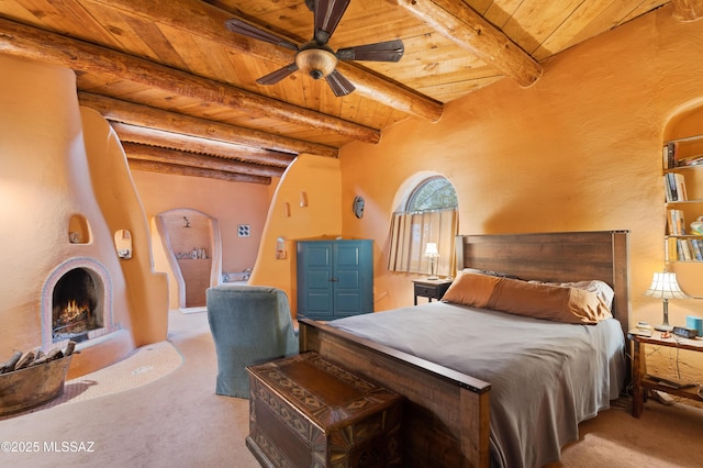 bedroom with wooden ceiling, a warm lit fireplace, and beam ceiling