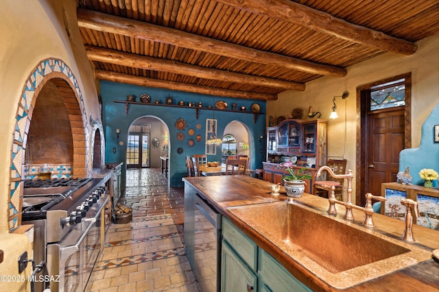 kitchen featuring arched walkways, green cabinetry, wood ceiling, stainless steel appliances, and a sink