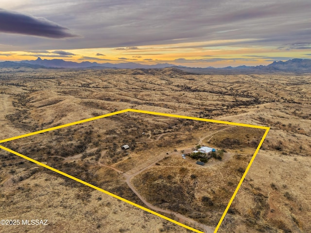 aerial view at dusk featuring a desert view and a mountain view