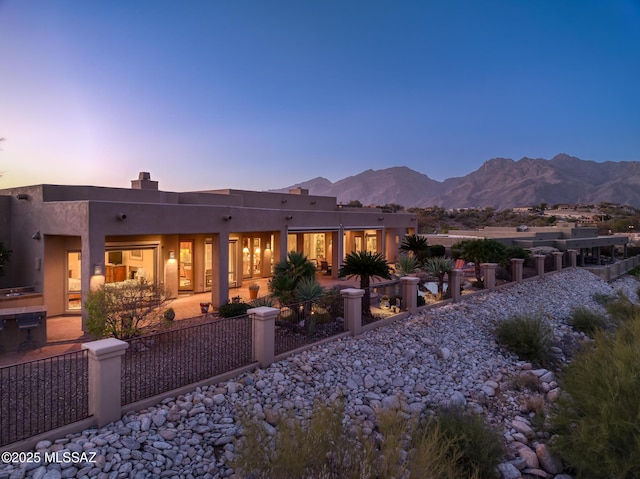 back of house with fence, a mountain view, and stucco siding