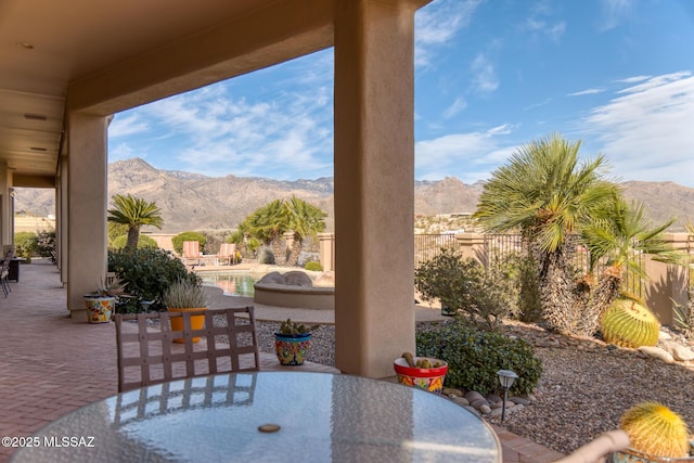 view of patio with a fenced backyard, a mountain view, an outdoor pool, and outdoor dining space