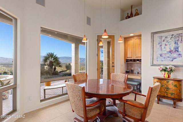 dining room with light tile patterned floors, a high ceiling, visible vents, and a mountain view