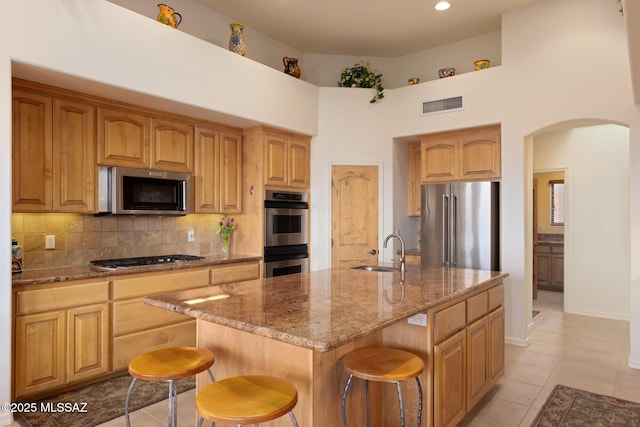 kitchen with a center island with sink, visible vents, appliances with stainless steel finishes, a sink, and a kitchen breakfast bar