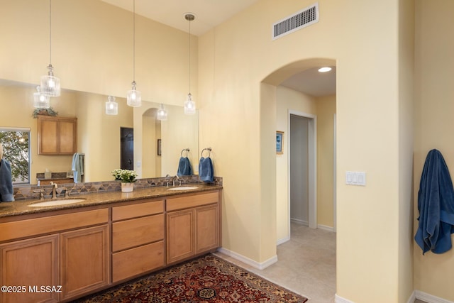 bathroom with double vanity, a sink, visible vents, and baseboards