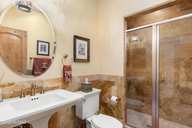 full bathroom with a sink, a shower stall, toilet, and tile walls