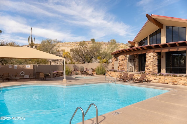 community pool with a patio area and fence