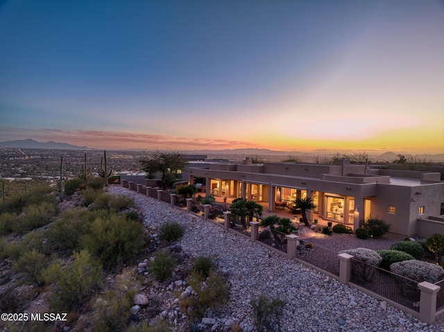 back of property with a fenced front yard, a mountain view, and stucco siding