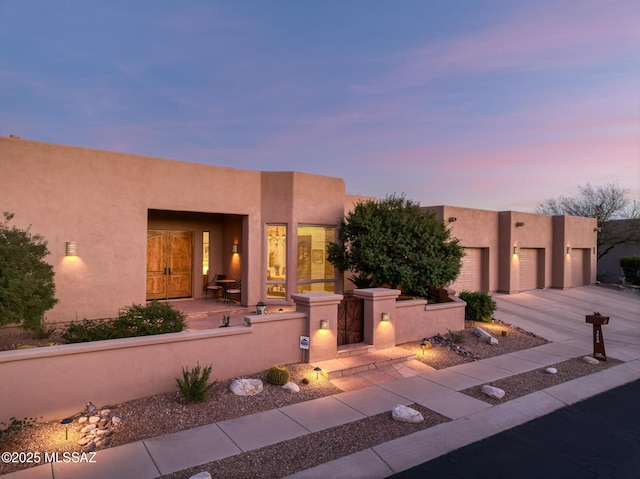 pueblo-style house with driveway and stucco siding