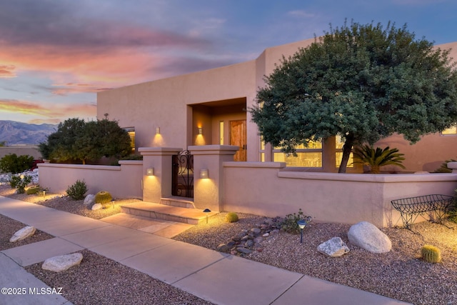 pueblo revival-style home featuring a fenced front yard and stucco siding