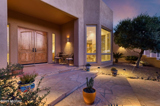 exterior entry at dusk featuring a patio area and stucco siding