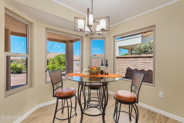 dining space featuring a notable chandelier, ornamental molding, light wood-style flooring, and baseboards