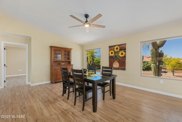 dining space with vaulted ceiling, light wood finished floors, a ceiling fan, and baseboards